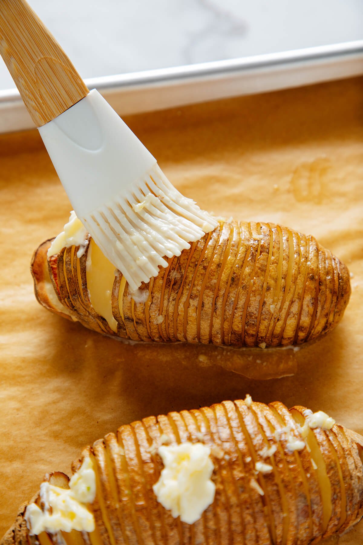 brushing Hasselback potatoes with butter